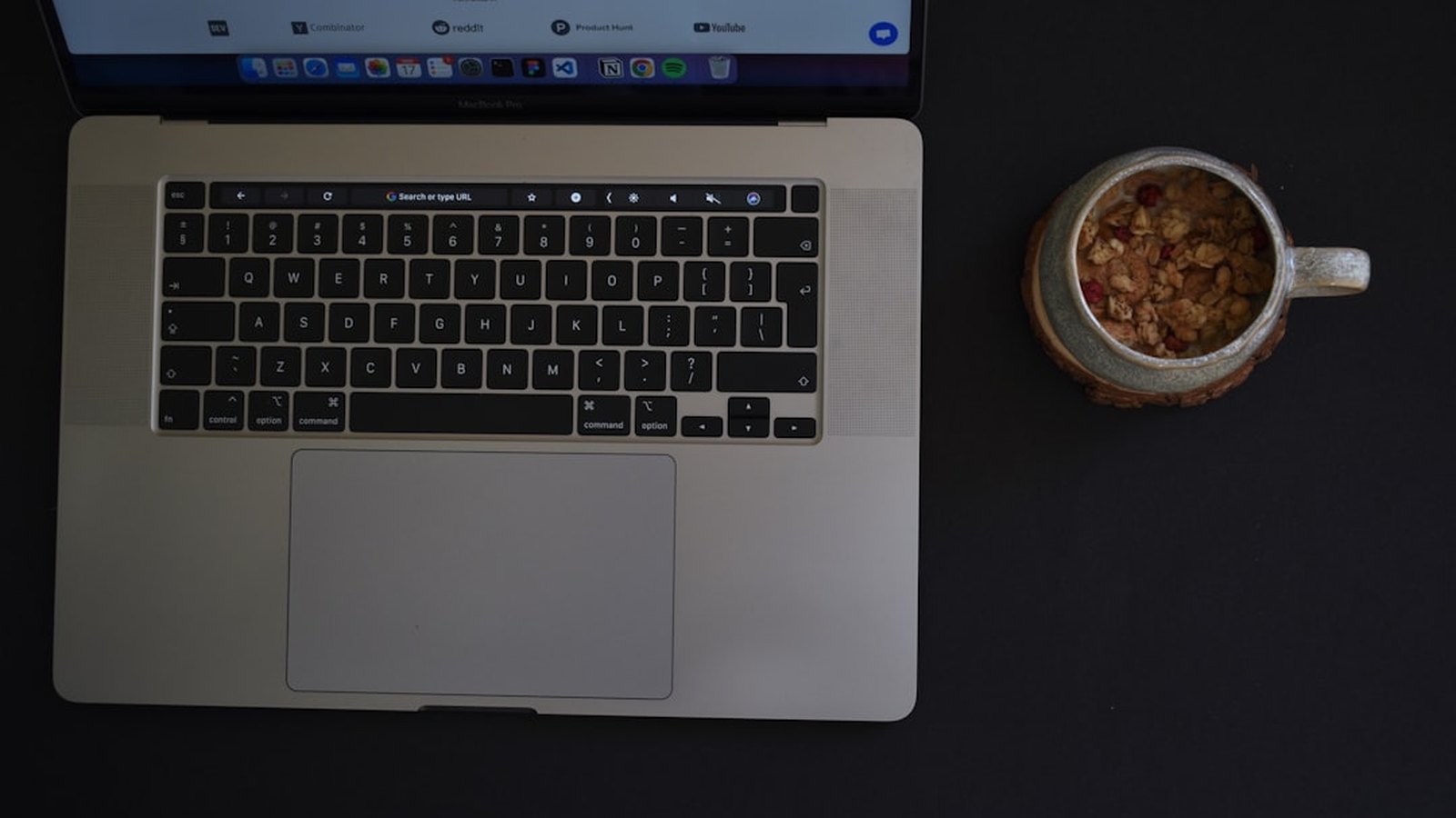 A laptop and a mug on a clean, dark desk: a calm daily workspace.